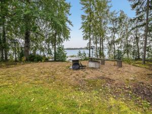 une table de pique-nique et un banc dans un champ avec un lac dans l'établissement Holiday Home Tyssinniemi by Interhome, à Hiukkajoki