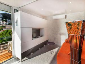 sala de estar con silla naranja y TV en Apartment Apt Naranja by Interhome, en Tossa de Mar