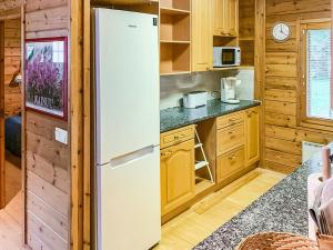 ein weißer Kühlschrank in einer Küche mit Holzschränken in der Unterkunft Holiday Home Lehtotuvat e by Interhome in Kotila + 11 Fotos