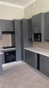 a kitchen with gray cabinets and a stove top oven at Ikhwezi guest house in East London