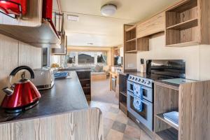 an rv kitchen with a red kettle on the counter at Lakeside, Thorpe Park Cleethorpes Static Caravan in Cleethorpes