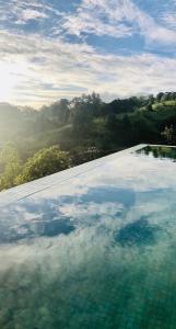 uma piscina com um reflexo do céu na água em Riverbank Resort Gampola em Gampola