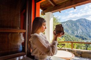 a woman taking a picture of a mountain through a window at Agriturismo Canales in Dorgali