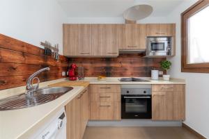 eine Küche mit Holzschränken und einer Spüle in der Unterkunft Casa Kaliste in Puerto Calero