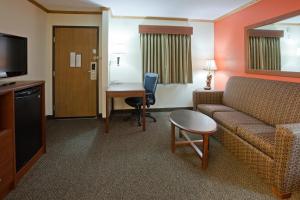 ein Hotelzimmer mit einem Sofa, einem Tisch und einem Schreibtisch in der Unterkunft AmericInn by Wyndham Virginia in Virginia