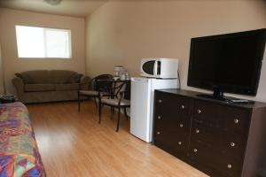 uma sala de estar com uma televisão de ecrã plano numa cómoda em Elks Motel em Keremeos