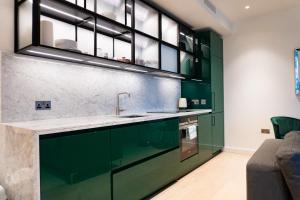 a kitchen with green cabinets and a sink at The Wardian, Canary Wharf in London