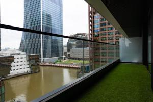 a balcony with a view of a river in a city at The Wardian, Canary Wharf in London