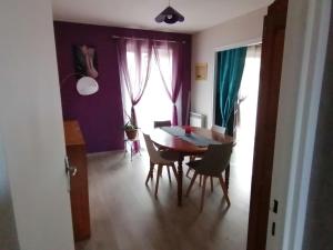 d'une salle à manger avec une table, des chaises et des murs violets. dans l'établissement Maison gai séjour à Bellac, à Bellac