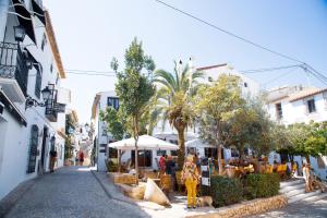 una strada con tavoli e ombrelloni in una città di Apartamentos Casa Mya ad Altea