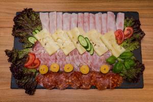 a plate of food with meats and cheese and vegetables at Penzion Hviezda in Bratislava