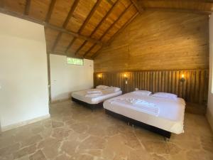 two beds in a room with wooden walls at Awa de Mar Playa in Tolú