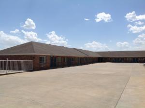 a large brick building with a large parking lot at Executive Inn Tulia in Tulia