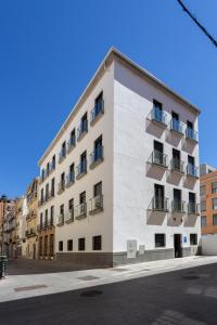 biały budynek z balkonami przy ulicy w obiekcie limehome Málaga Calle Ancha del Carmen - Digital Access w Maladze