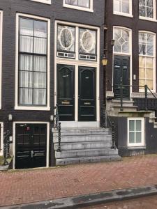a building with black doors and stairs on a street at Beautiful Apartment City Centre Amsterdam in Amsterdam