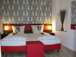 a bedroom with a red and white bed with a red bench at Cityhotel Ahlen Garni in Ahlen