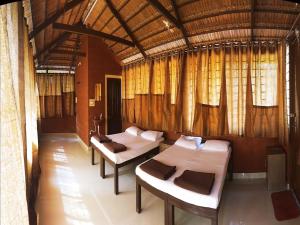 2 camas en una habitación con cortinas y ventanas en CS County Resort, en Sakleshpur