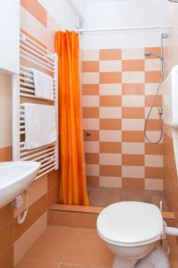 La salle de bains est pourvue d'un rideau de douche orange et de toilettes. dans l'établissement Apartments Garden-Cavtat, à Cavtat