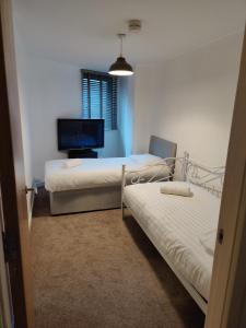 a room with two beds and a flat screen tv at Cornhill Apartment by Serviced Living Liverpool in Liverpool