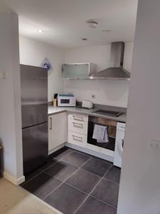 una cocina con nevera de acero inoxidable y armarios blancos en Cornhill Apartment by Serviced Living Liverpool, en Liverpool