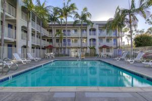 a swimming pool in front of a hotel with chairs and a building at Motel 6-Oceanside, CA in Oceanside