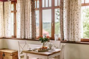 a table and chairs in a room with windows at Villa Filmowiec in Polanica-Zdrój