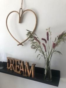un cœur suspendu sur un mur avec un vase de fleurs dans l'établissement Auron Joli appartement, à Auron