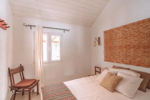 a bedroom with a bed and a chair and a window at Cá Estamos ~ Hortacasa Portugal in Santiago do Cacém
