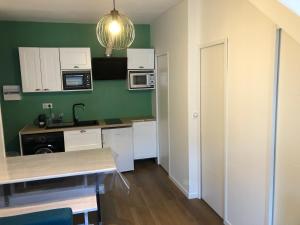 a kitchen with green walls and white cabinets and a table at Appart 6 pers rénové en plein cœur de Cauterets in Cauterets +3 photos