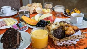 uma mesa coberta com um cesto de comida e sumo de laranja em Pousada Araucária em Campos do Jordão