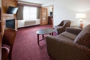a hotel room with chairs and a table and a fireplace at AmericInn by Wyndham White Bear Lake St. Paul in White Bear Lake