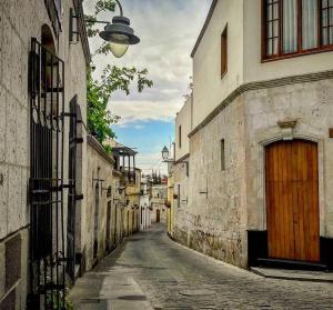 un callejón con un edificio con una puerta de madera en El MONARCA AREQUIPA, en Arequipa