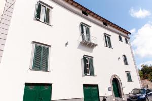ein weißes Gebäude mit grünen Türen und einem Auto in der Unterkunft Back to Sorrento in Sant'Agnello