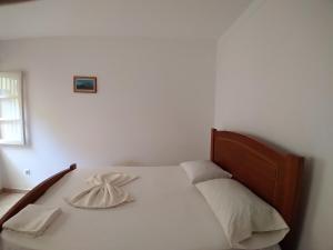 聖菲利佩的住宿－Pensão Domingas，卧室内的一张白色床和木制床头板