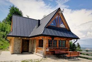 a log cabin with a metal roof and a table at Domek w Górach Chatka Rogasiowa in Rytro