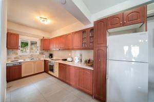 eine Küche mit Holzschränken und einem weißen Kühlschrank in der Unterkunft Villa Mounda Poseidon, Sea View Villa with pool in Ratzaklíon