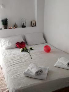 雅典的住宿－Thisio Loft，一张白色的床,有两朵玫瑰和红色气球