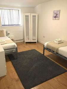 een slaapkamer met 2 bedden en een tapijt bij Large Ground Floor Pet Friendly 2 Bedroom Apartment with FREE Parking in Loughborough