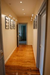 - un couloir avec du parquet et des photos sur les murs dans l'établissement Maison de vacances _ Le Bas Manoir, à Bretteville-sur-Odon