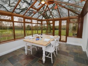 a conservatory with a table and chairs and windows at 5 Grange Cottages in Southam