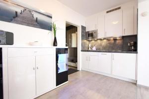 eine Küche mit weißen Schränken und schwarzen Arbeitsplatten in der Unterkunft Kaiserhof Oceanview in Kellenhusen