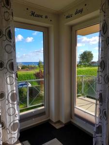 ein Zimmer mit zwei Fenstern mit der Aufschrift „Schönen Tag noch“ in der Unterkunft Kaiserhof Oceanview in Kellenhusen