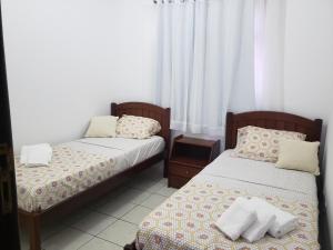 duas camas num quarto com cortinas brancas em Confortável apartamento próximo à Ponta Negra em Natal
