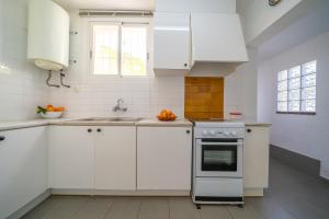 eine weiße Küche mit einer Spüle und einem Herd in der Unterkunft Villa Vista Lux, Piscina privada y zona exterior con vista Mar in Tossa de Mar