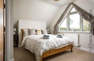 a bedroom with a bed and a large window at Hetty's Stables in Yanworth