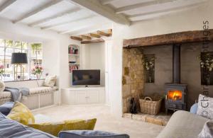 a living room with a fireplace and a tv at Stanley Cottage in Chipping Campden