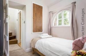 a white bedroom with a bed and a window at Stanley Cottage in Chipping Campden