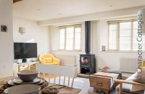 a living room with a wood stove and a couch at Barn End Cottage in Chipping Campden