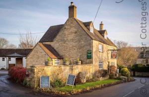 ein altes Steingebäude mit einem Schild davor in der Unterkunft Barn End Cottage in Chipping Campden