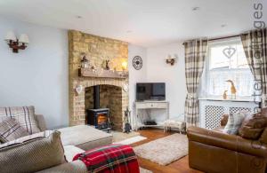 a living room with a couch and a fireplace at Inglenook Cottage in Bourton on the Water